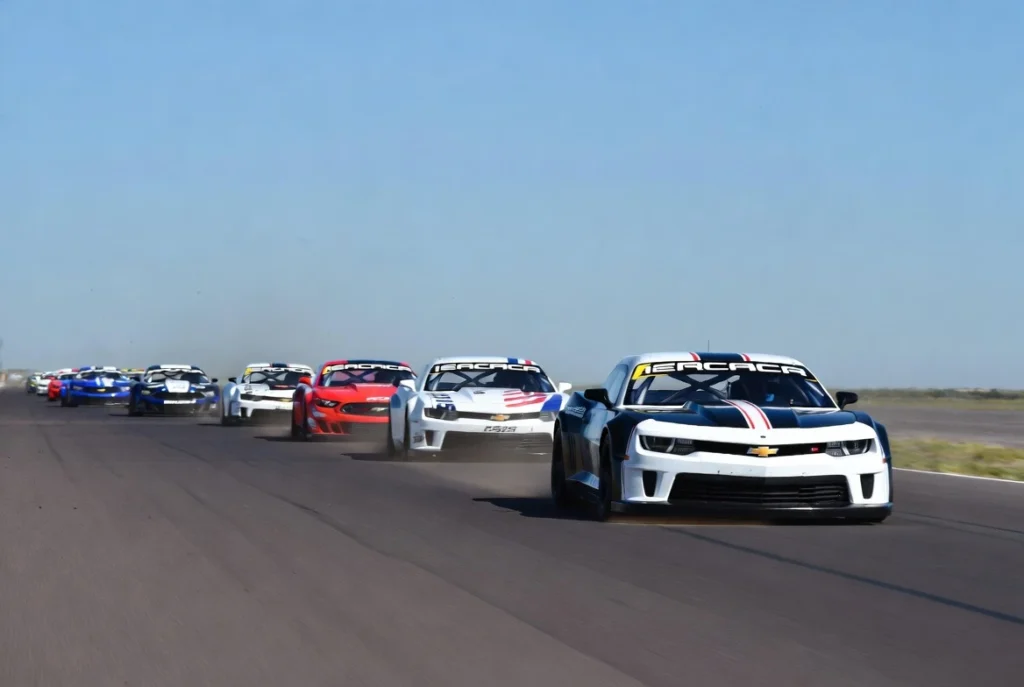 tc-en-toay-2025-00 Pelotón de autos de Turismo Carretera de nueva generación corriendo a alta velocidad en la recta principal durante el TC en Toay 2025, La Pampa.